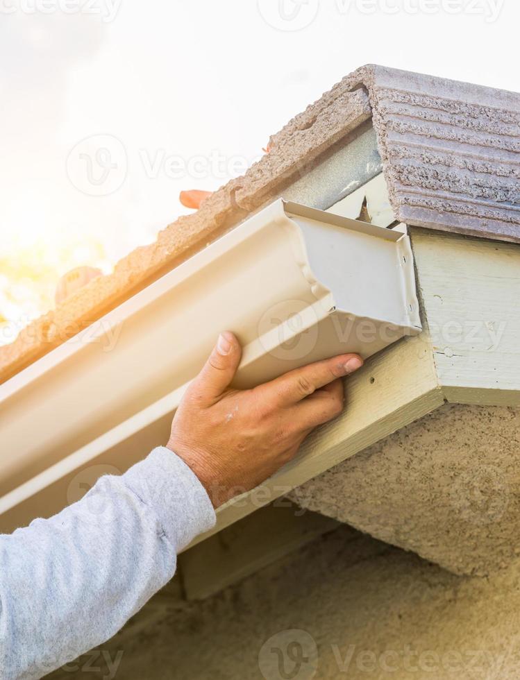 Worker Attaching Aluminum Rain Gutter to Fascia of House. photo