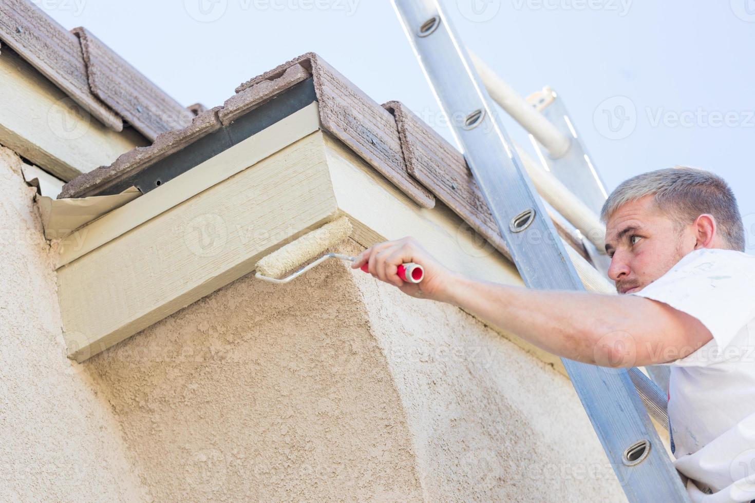 pintor profesional que usa un rodillo pequeño para pintar la fascia de la casa foto