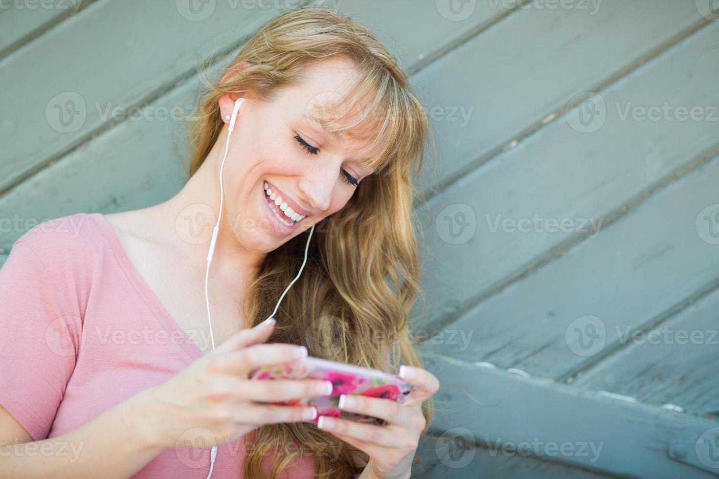 Outdoor Portrait of Young Adult Brown Eyed Woman Listening To Music with Earphones on Her Smart Phone. photo