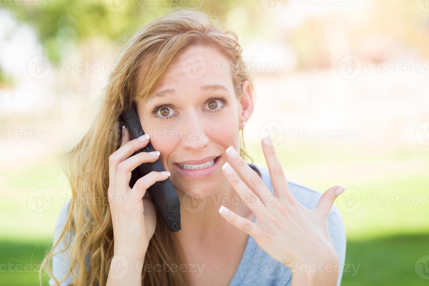 Stunned Young Woman Outdoors Talking on Her Smart Phone. photo