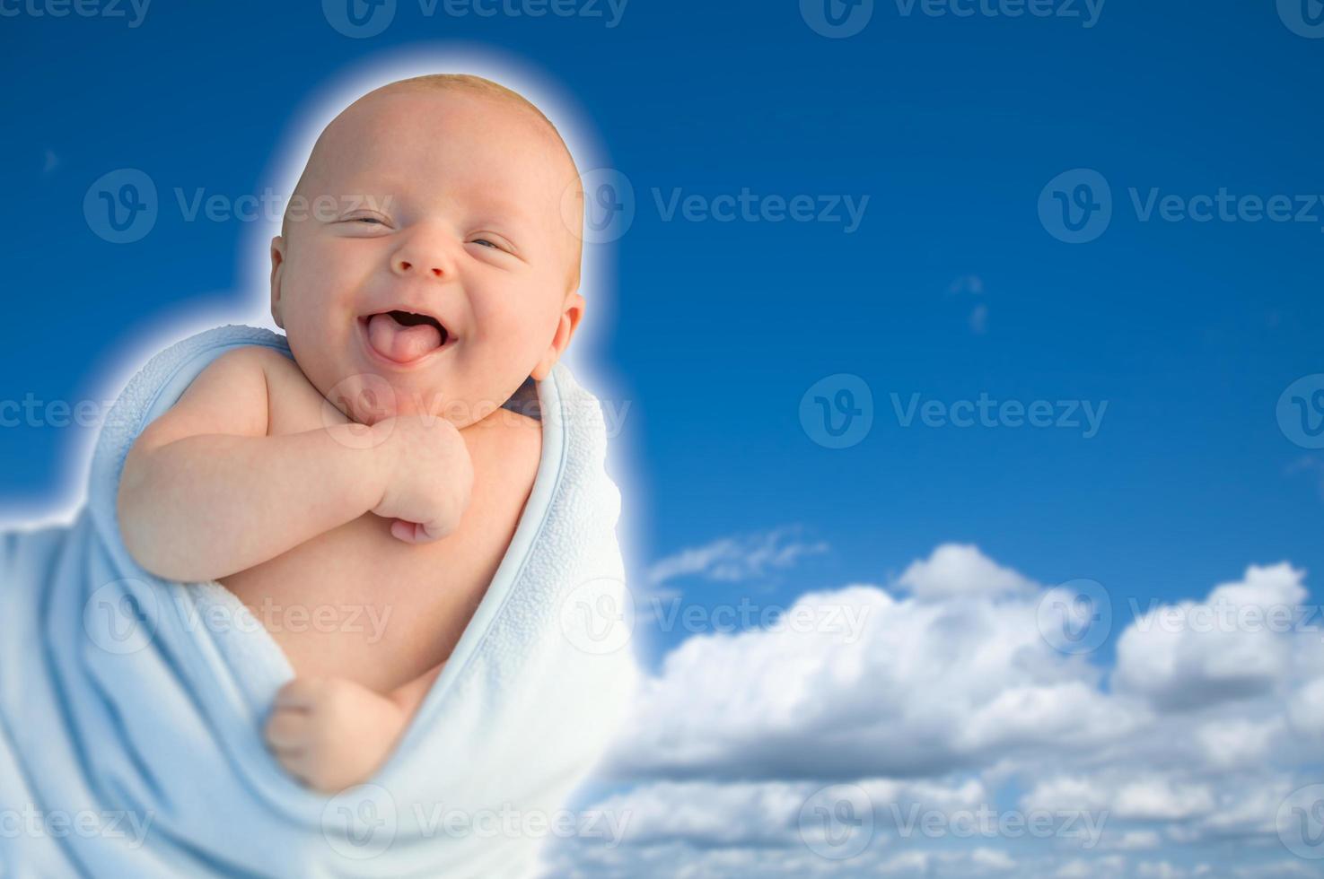 hermoso niño riendo envuelto en su manta con un fondo de cielo azul. foto