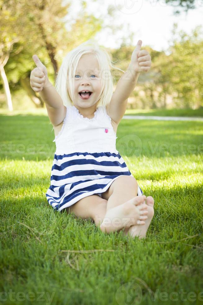 Cute Little Girl with Thumbs Up in the Grass photo