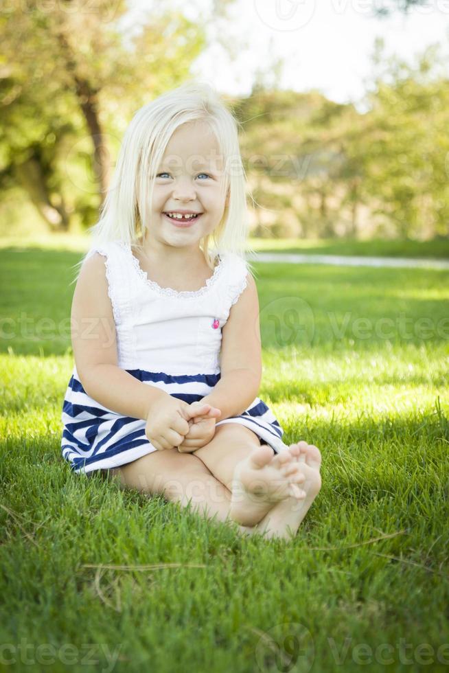 Cute Little Girl Sitting and Laughing in the Grass photo