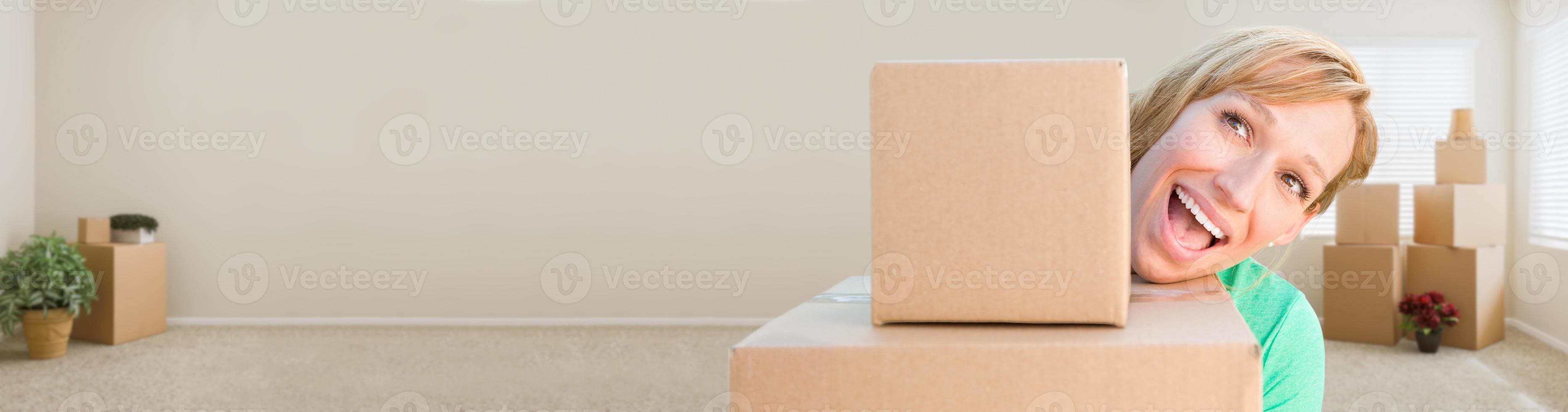 Banner of Happy Young Adult Woman Holding Moving Boxes In Empty Room In A New House. photo