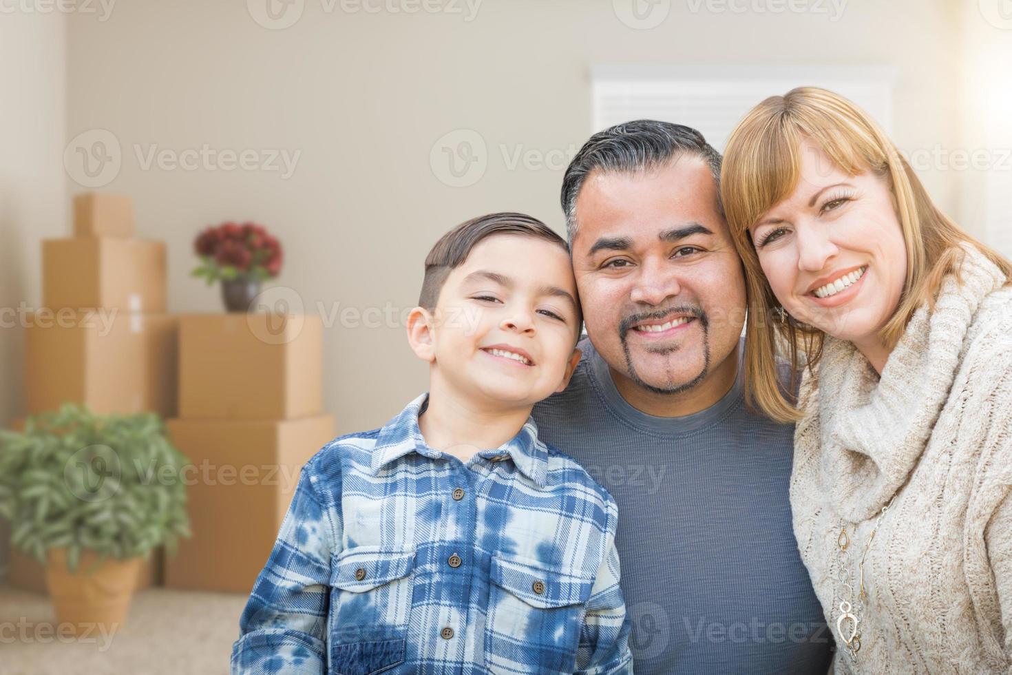 Mixed Race Family In Empty Room With Moving Boxes and Plants. photo