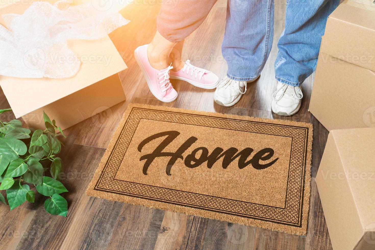 hombre y mujer desempacando cerca de la alfombra de bienvenida en casa, cajas móviles y plantas foto