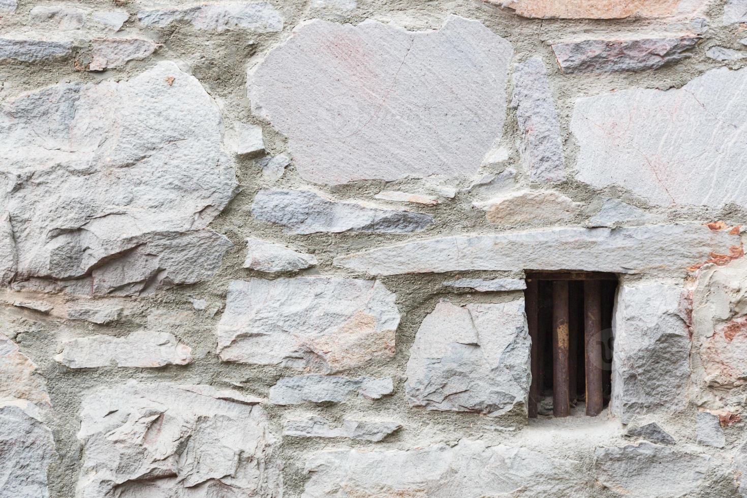 Old Stone Wall With Small Iron Barred Prison Cell Window photo