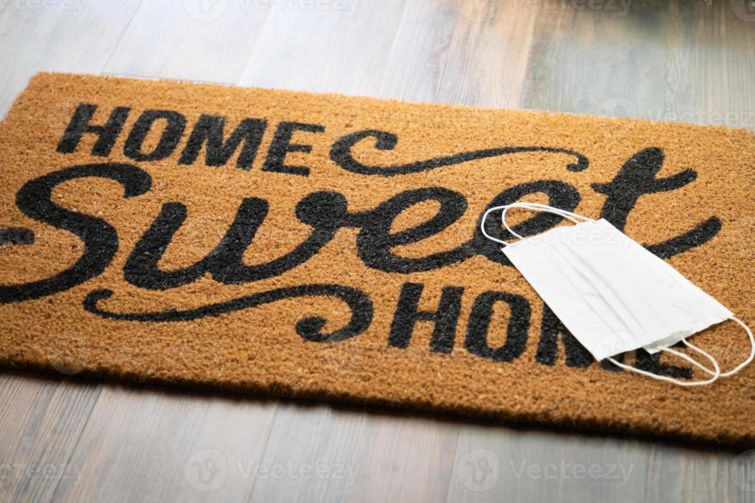 Medical Face Masks Rests on Home Sweet Home Welcome Mat Amidst The Coronavirus Pandemic photo