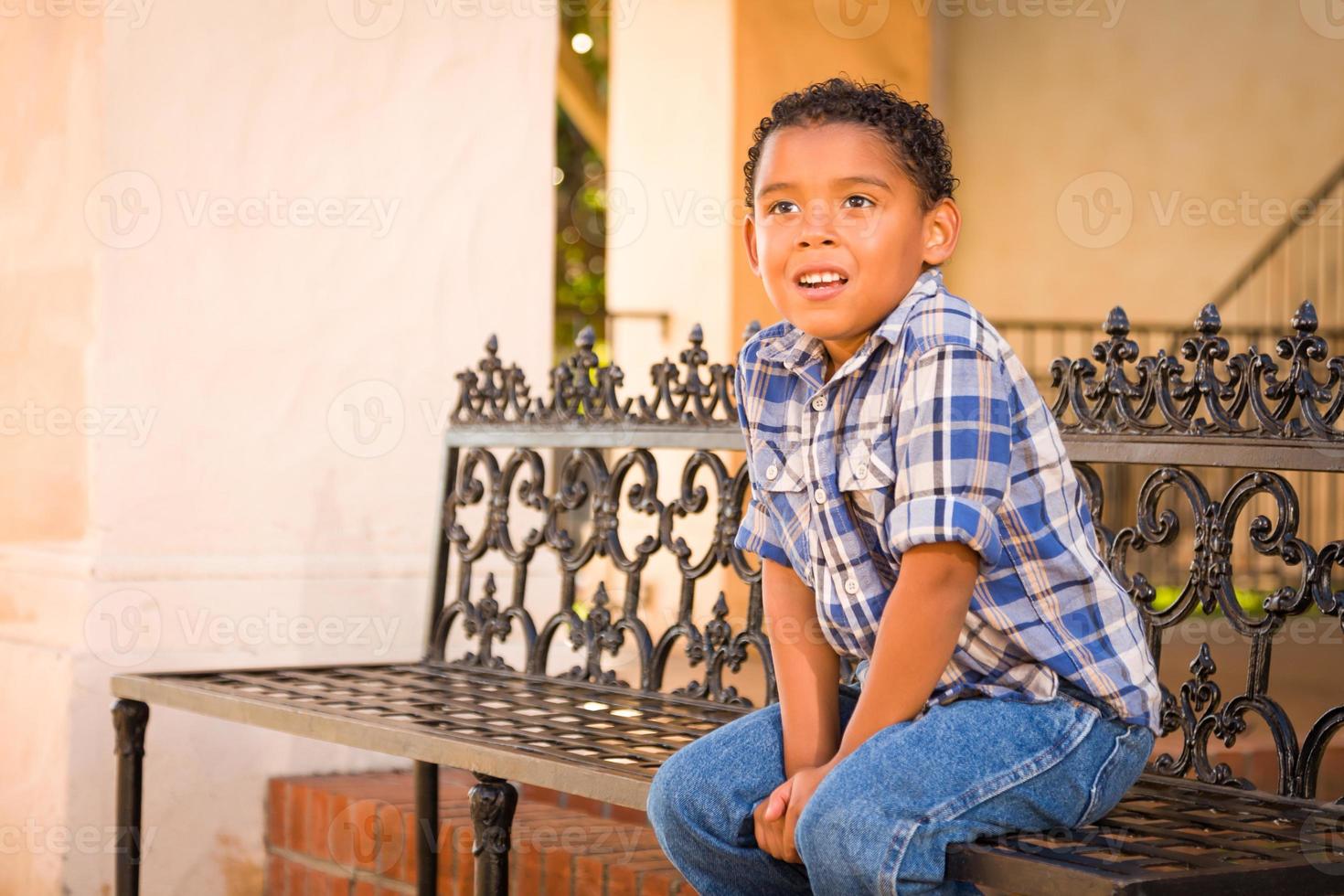 Guapo chico afroamericano y mexicano sentado en un banco del parque foto