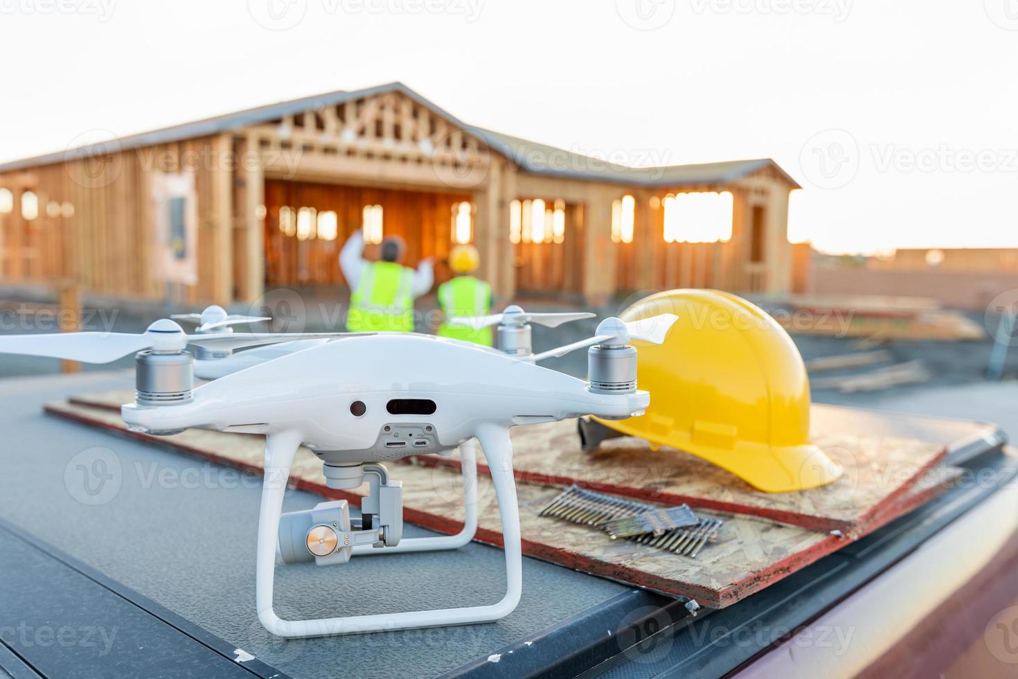 drone quadcopter junto al casco de casco en el sitio de construcción con trabajadores detrás foto