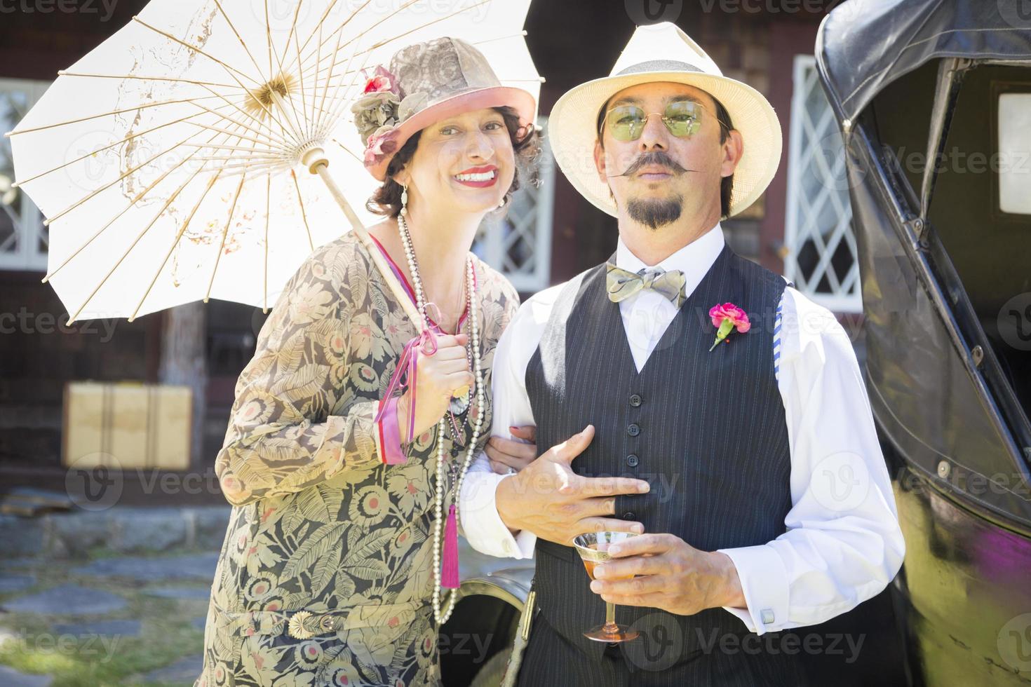 pareja de raza mixta vestida a la moda de la década de 1920 bebiendo champán foto