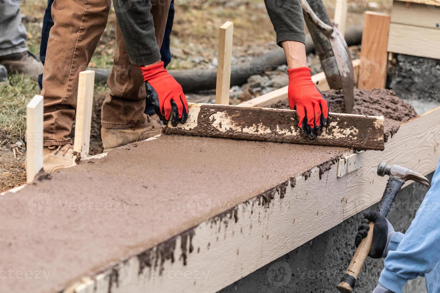 Construction Worker Leveling Wet Cement Into Wood Framing photo