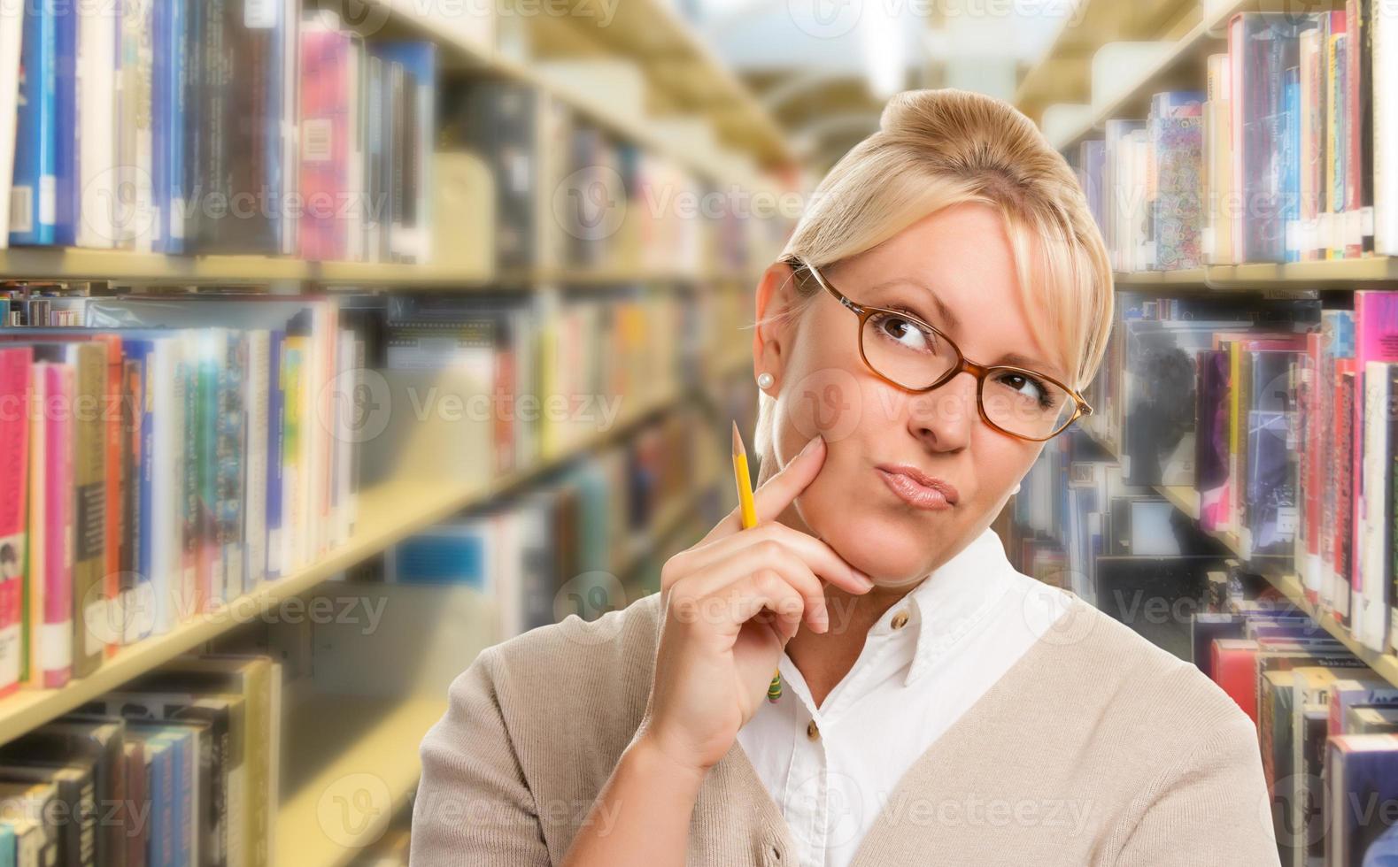 hermoso estudiante expresivo o profesor con lápiz en la biblioteca. foto