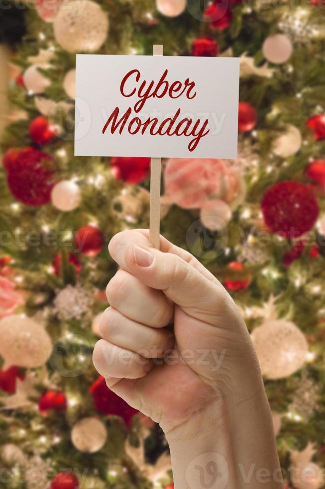 Hand Holding Cyber Monday Card In Front of Decorated Christmas Tree. photo