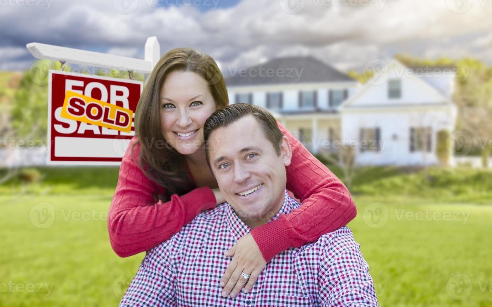 Couple In Front of Sold For Sale Sign and House photo