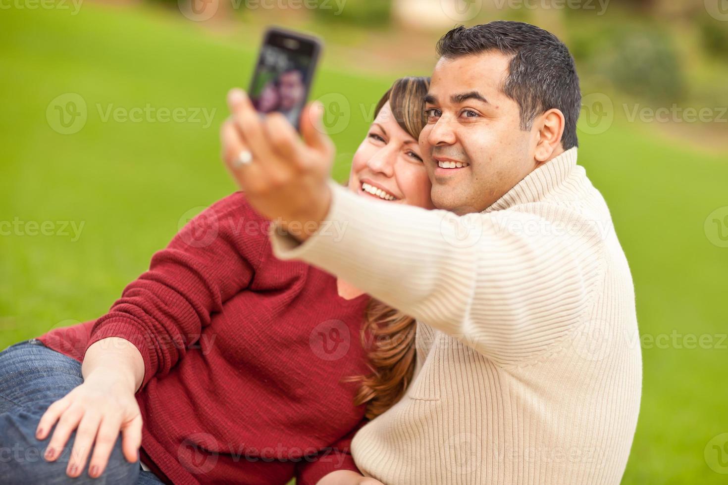 atractiva pareja de raza mixta tomando autorretratos en el parque foto