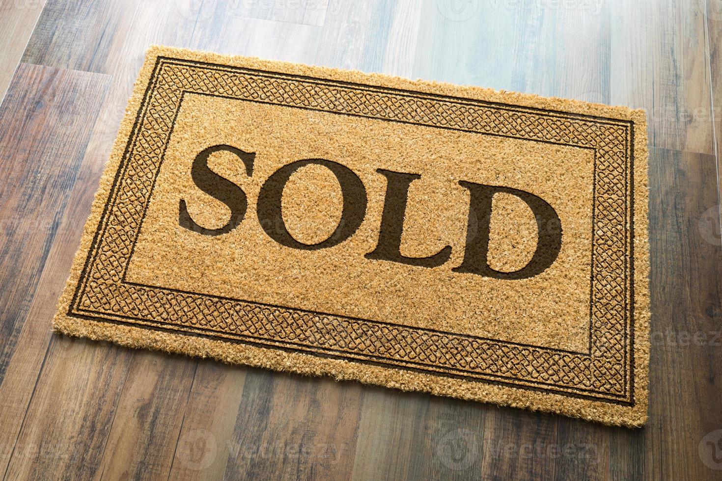 Sold Welcome Mat On A Wood Floor Background photo