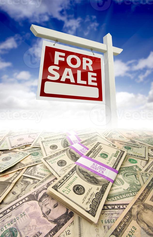 Stacks of Money Fading Off and For Sale Real Estate Sign photo