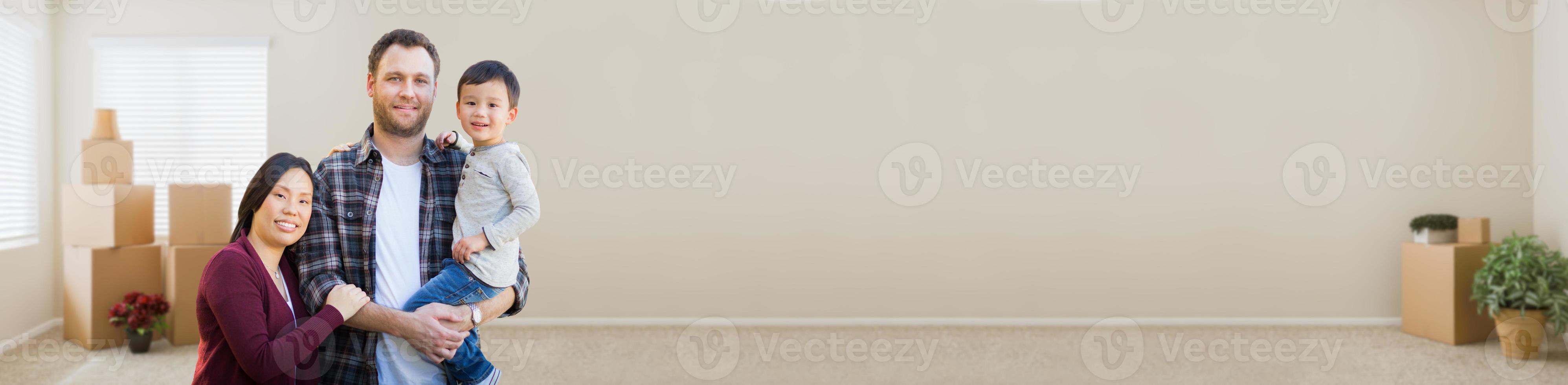 Banner of Mixed Race Chinese and Caucasian Parents and Child Inside Empty Room with Moving Boxes. photo