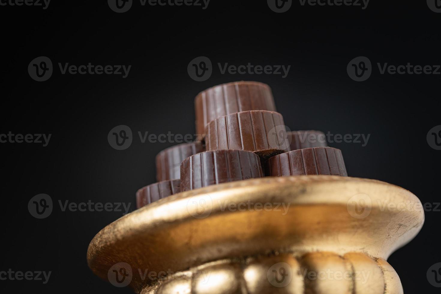 Stack of Fine Chocolates On Golden Pillar Dish With Dark Background photo