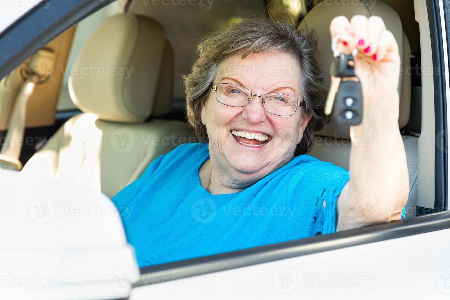 feliz anciana sentada en un auto nuevo sosteniendo las llaves foto