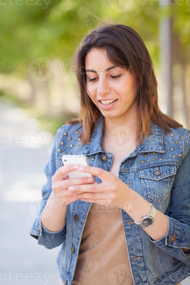 hermosa joven étnica usando su teléfono inteligente afuera. foto