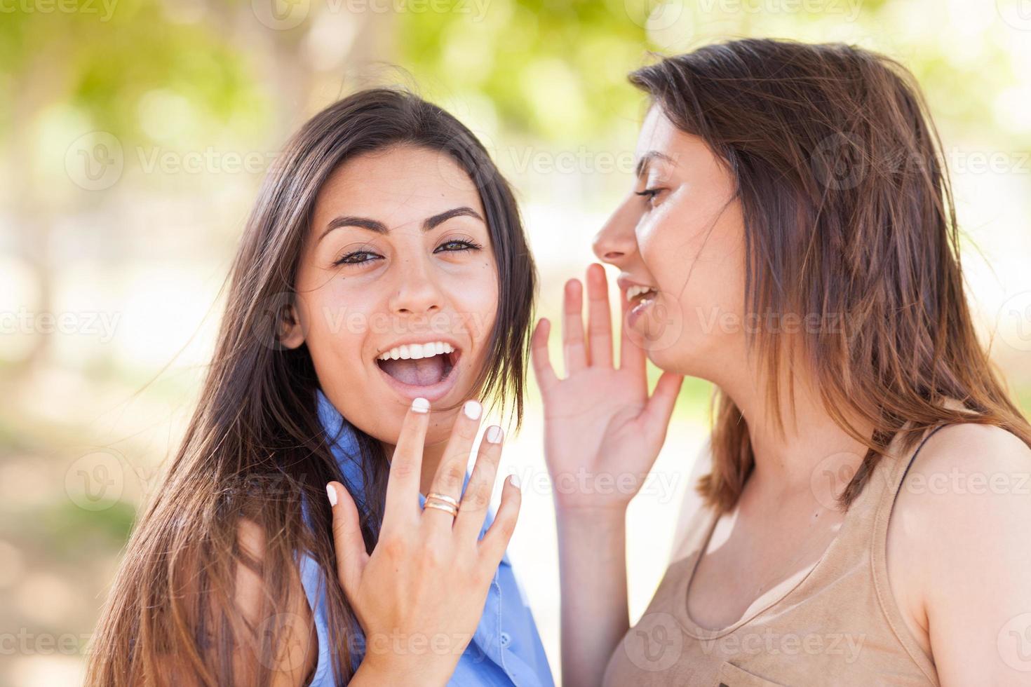 Two Beautiful Ethnic Twin Sisters Whispering Secrets Outdoors. photo