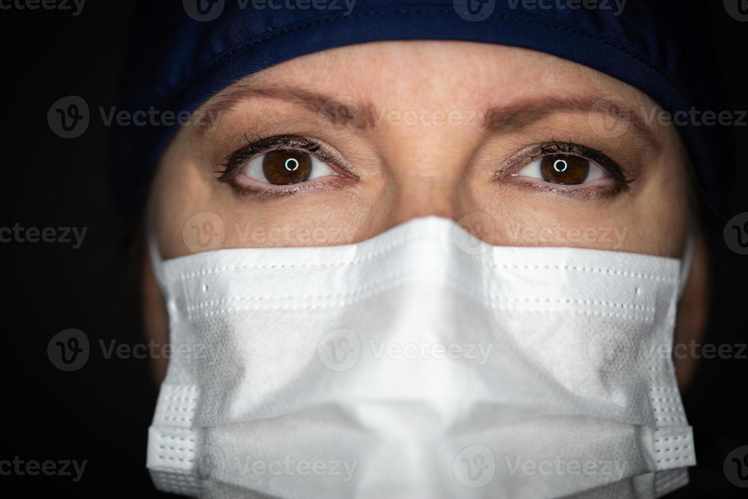 Female Doctor or Nurse Wearing Medical Face Mask on Dark Background photo