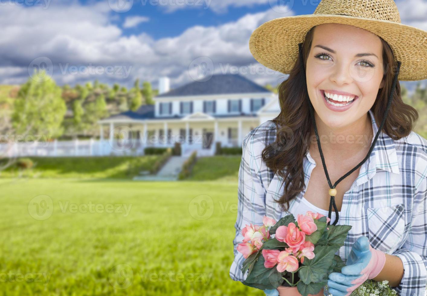 mujer joven haciendo jardinería frente a una hermosa casa foto