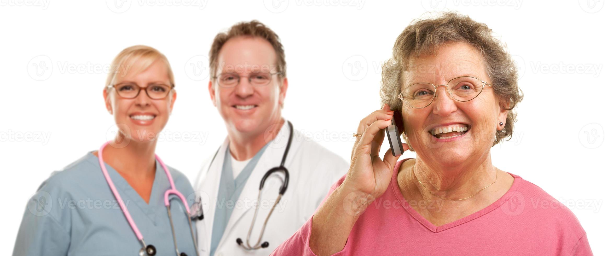 Happy Senior Woman Using Cell Phone and Doctors Behind photo