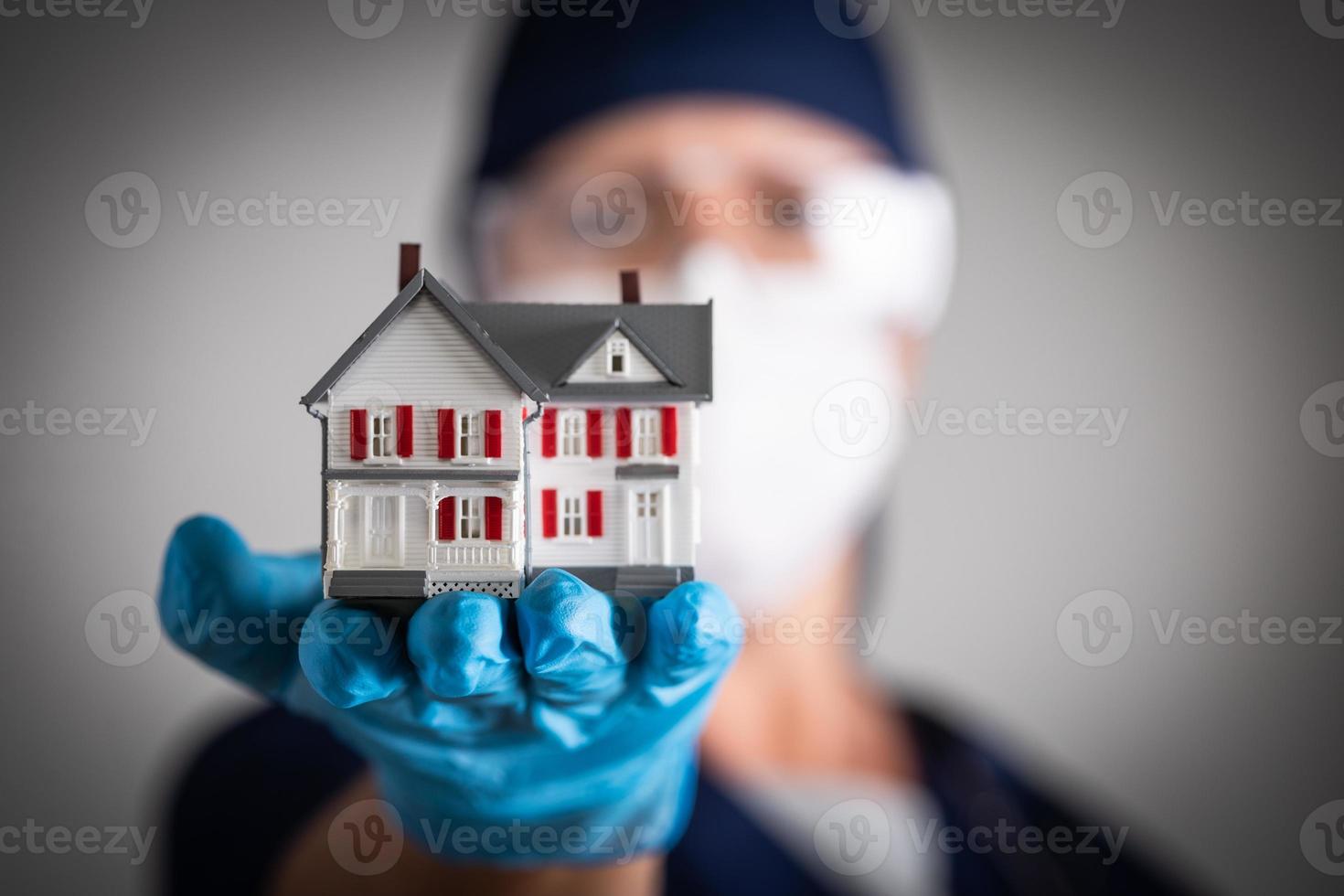 doctora o enfermera con guantes quirúrgicos sosteniendo una casa modelo foto