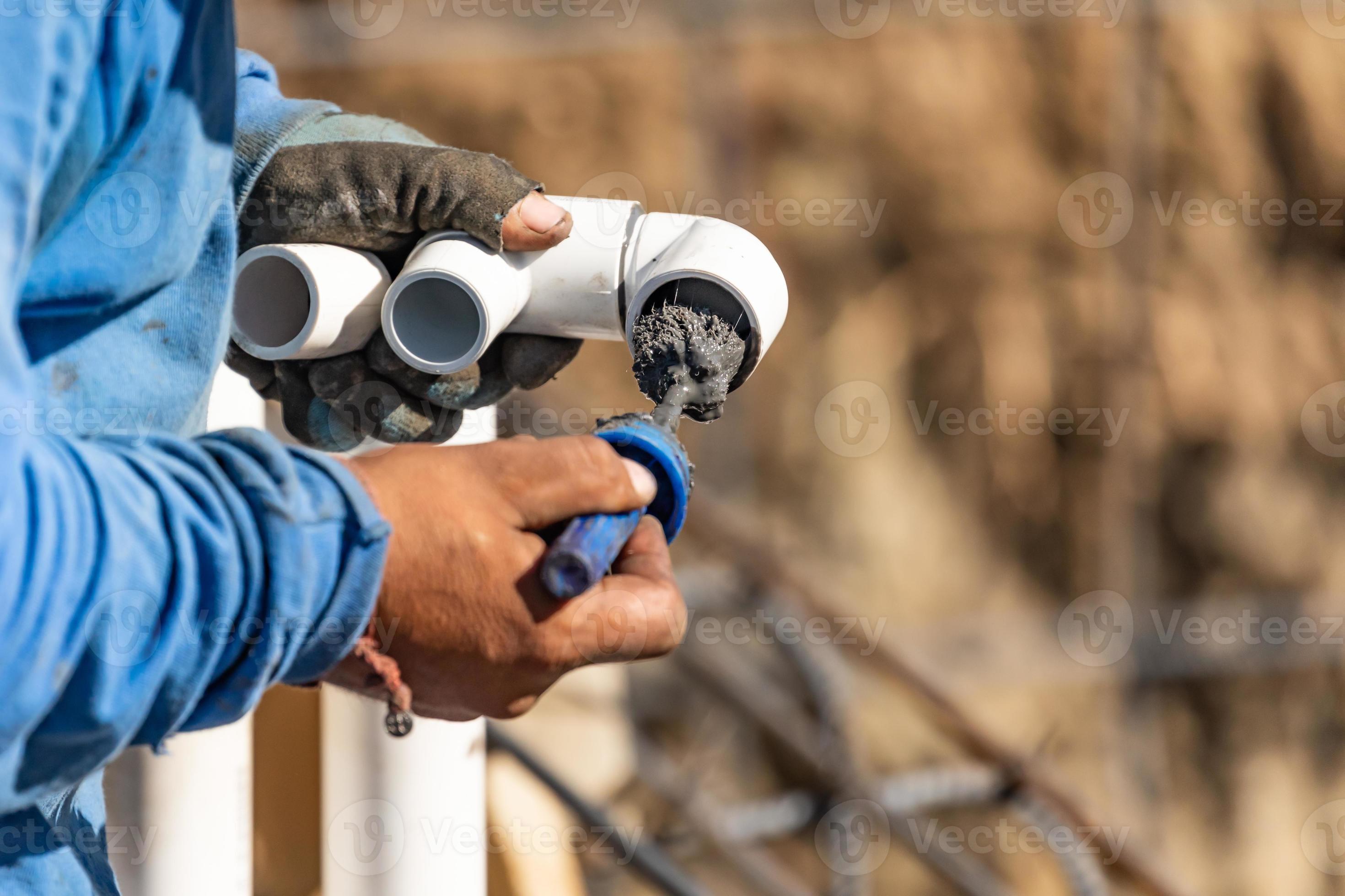 Plumber Applying Pipe Cleaner, Primer and Glue to PVC Pipe At Construction Site 16426457 Stock