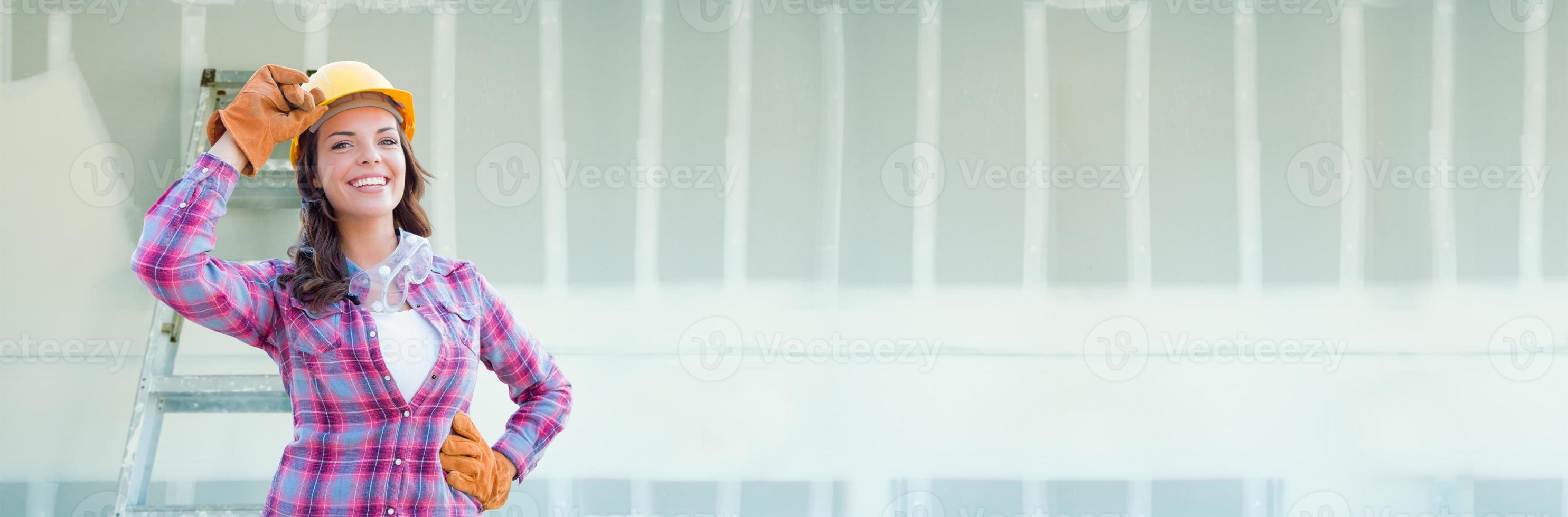 Female Contractor Wearing Hard Hat Against Dywall Banner Background with Ladder photo