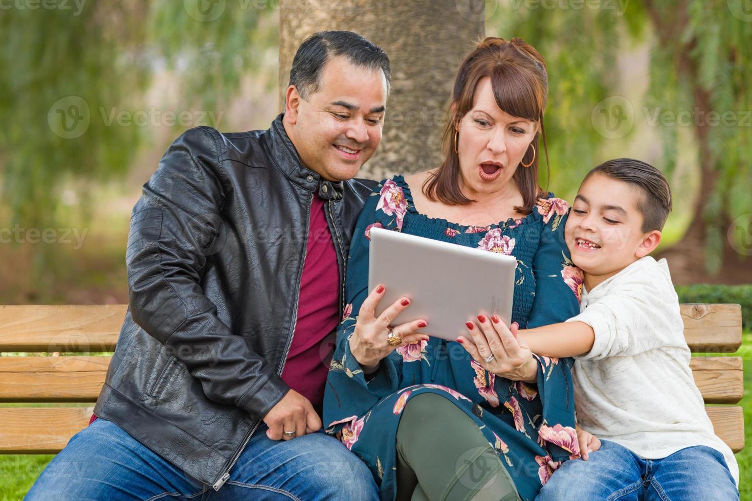 Caucasian Mother and Hispanic Father Using Computer Tablet With Mixed Race Son Outdoors photo
