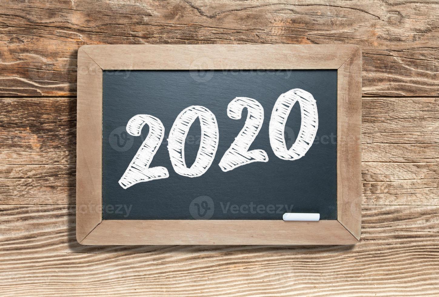 2020 Written on Slate Chalk Board Against Aged Wood Background photo