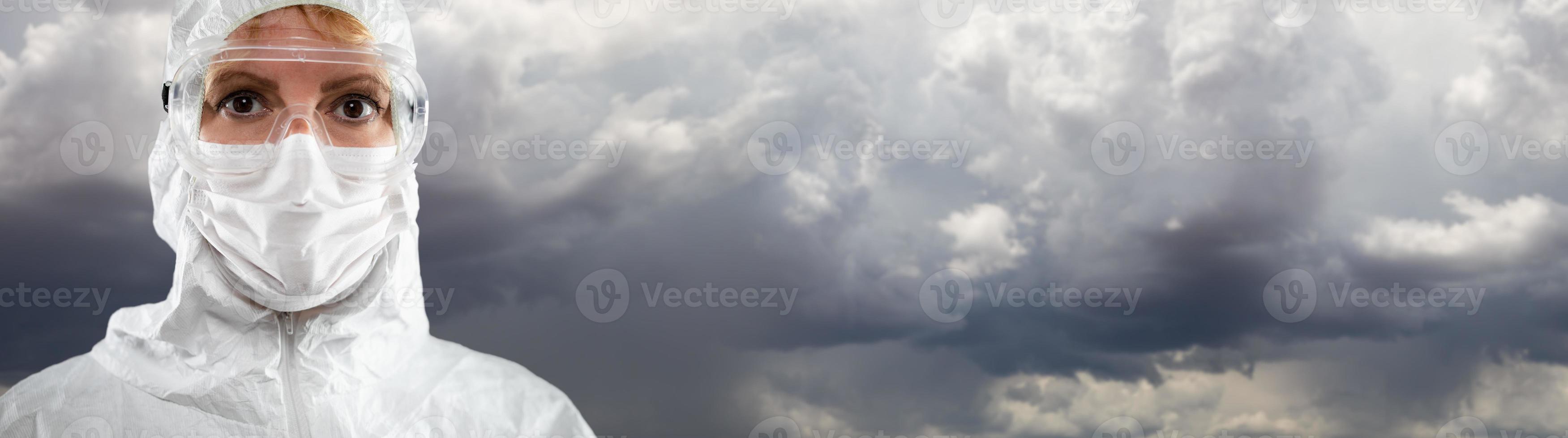 Female Medical Worker Wearing Protective Face Mask and Gear Against Cloudy Stormy Sky photo