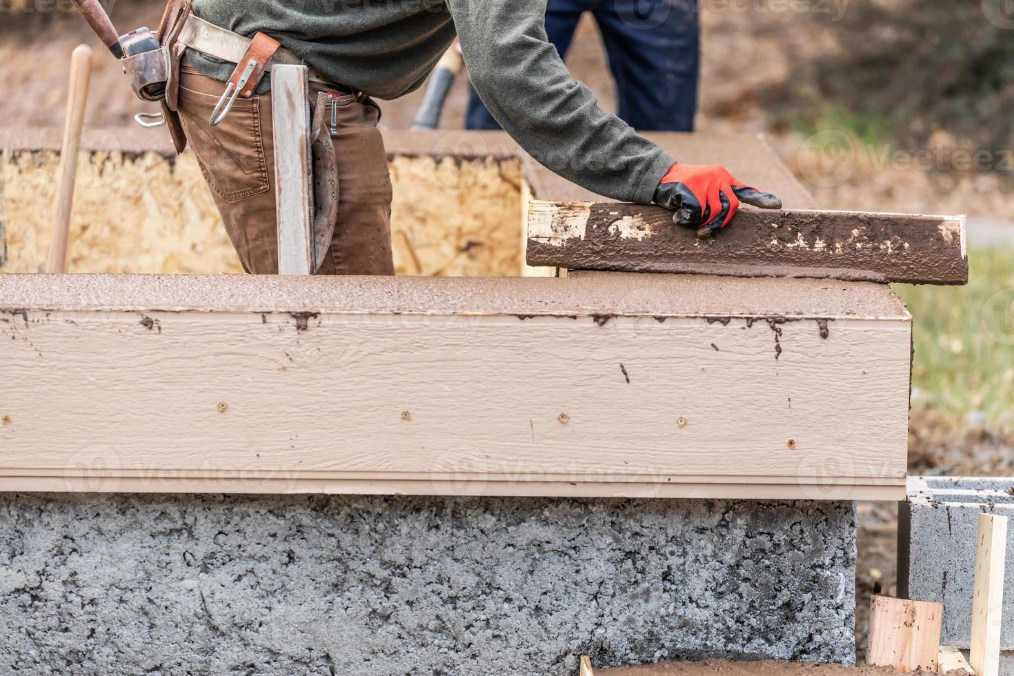 Construction Worker Leveling Wet Cement Into Wood Framing 16427246
