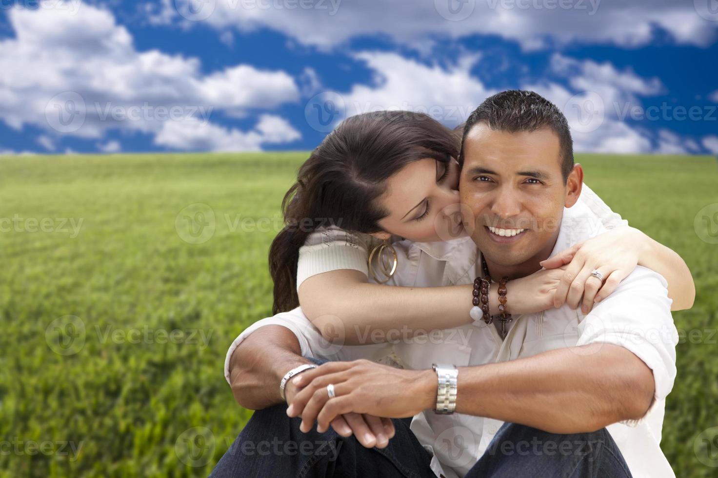 Hispanic Couple Sitting in Grass Field photo