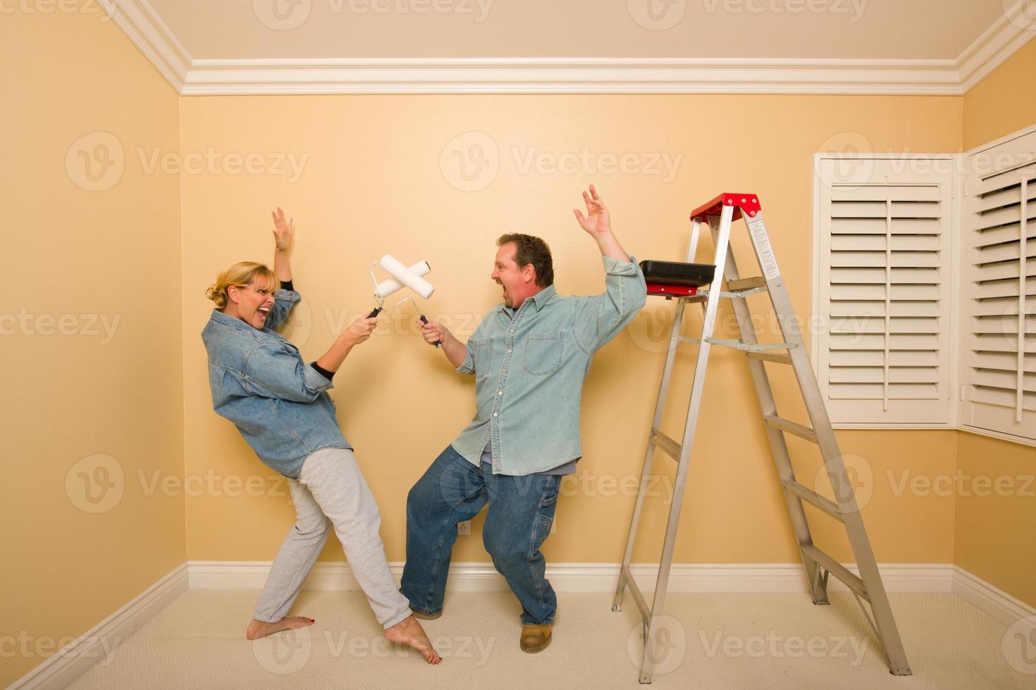 Fun Couple Playing Sword Fight with Paint Rollers photo