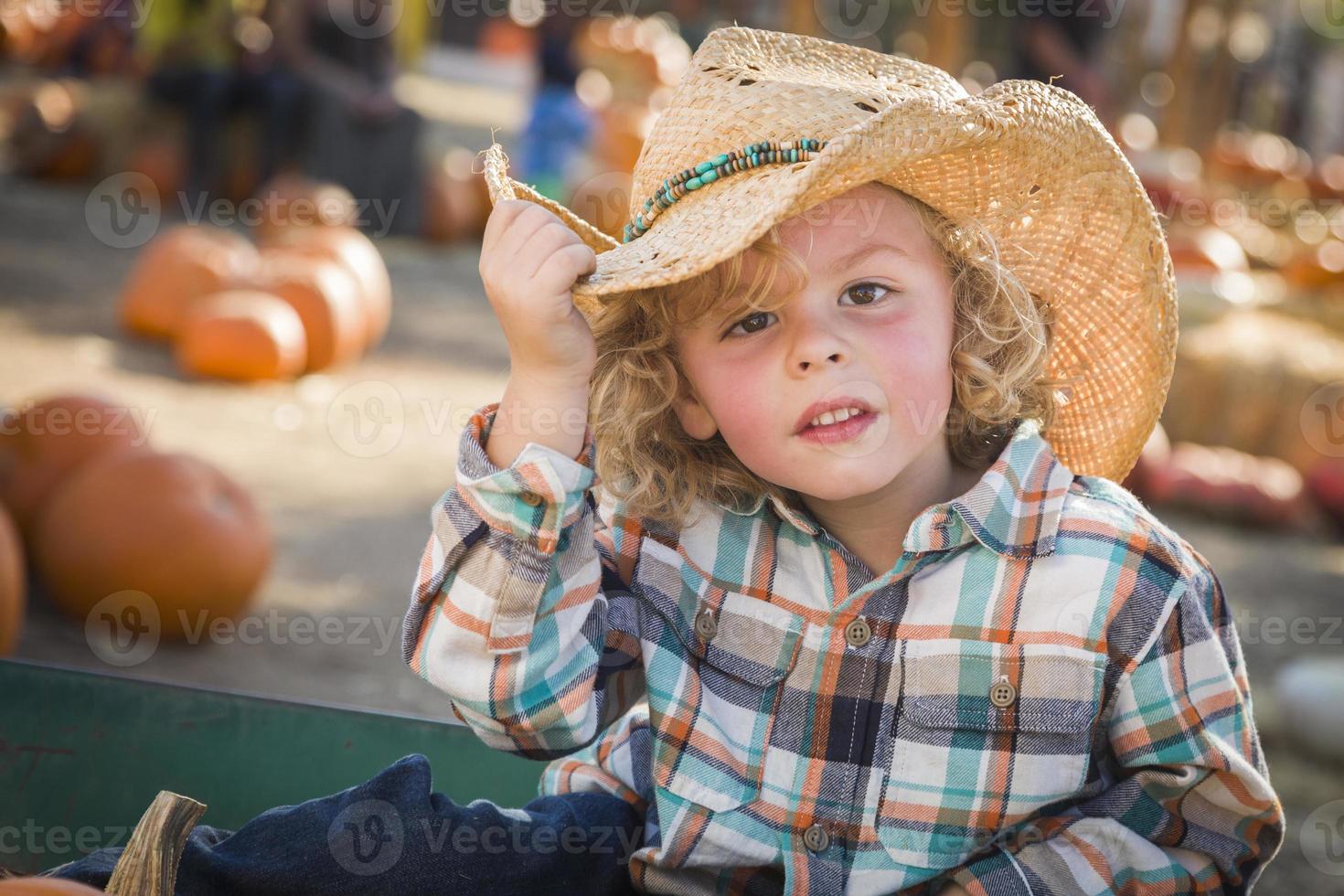 niño pequeño con sombrero de vaquero en el huerto de calabazas foto