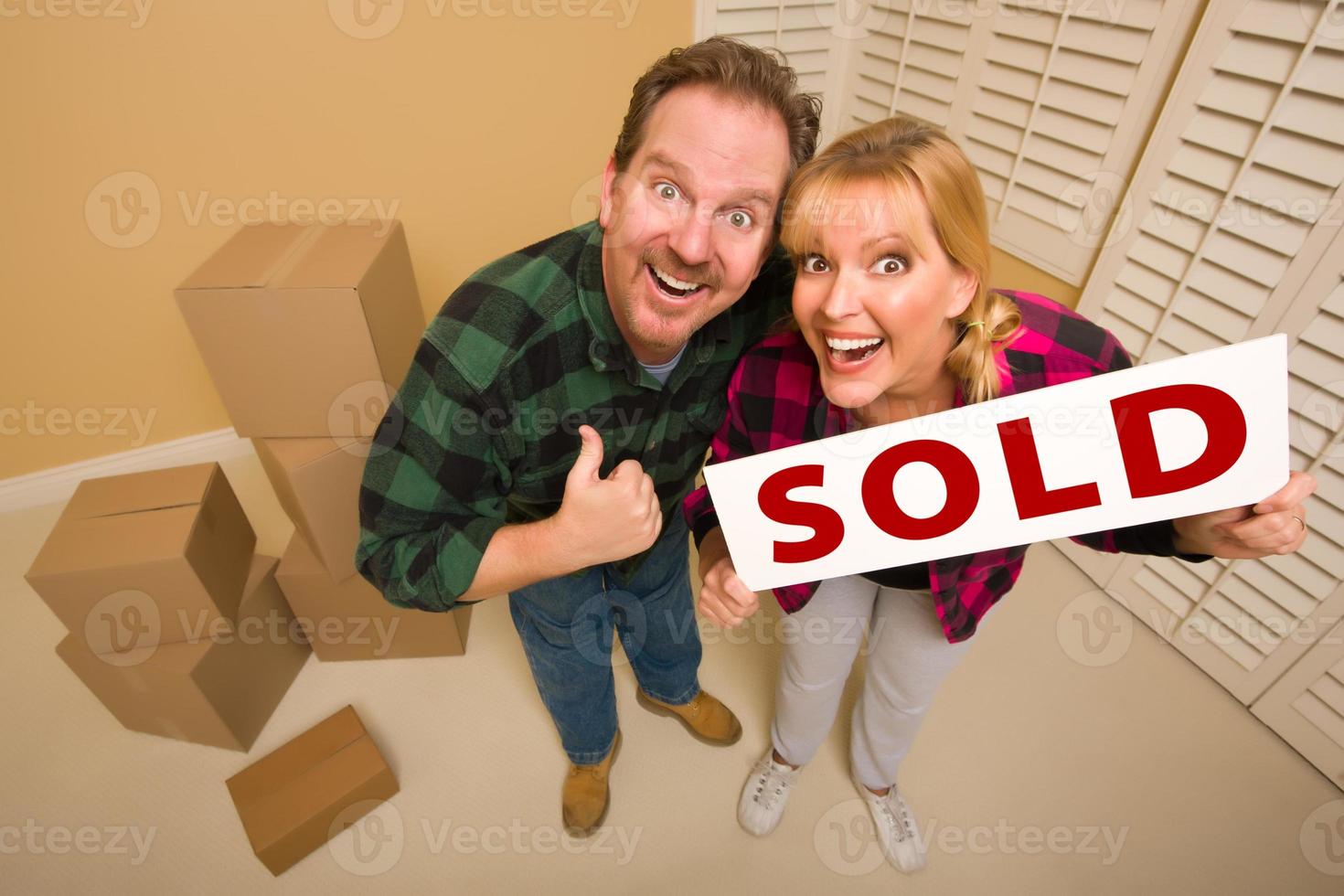 Goofy Couple Holding Sold Sign Surrounded by Boxes photo
