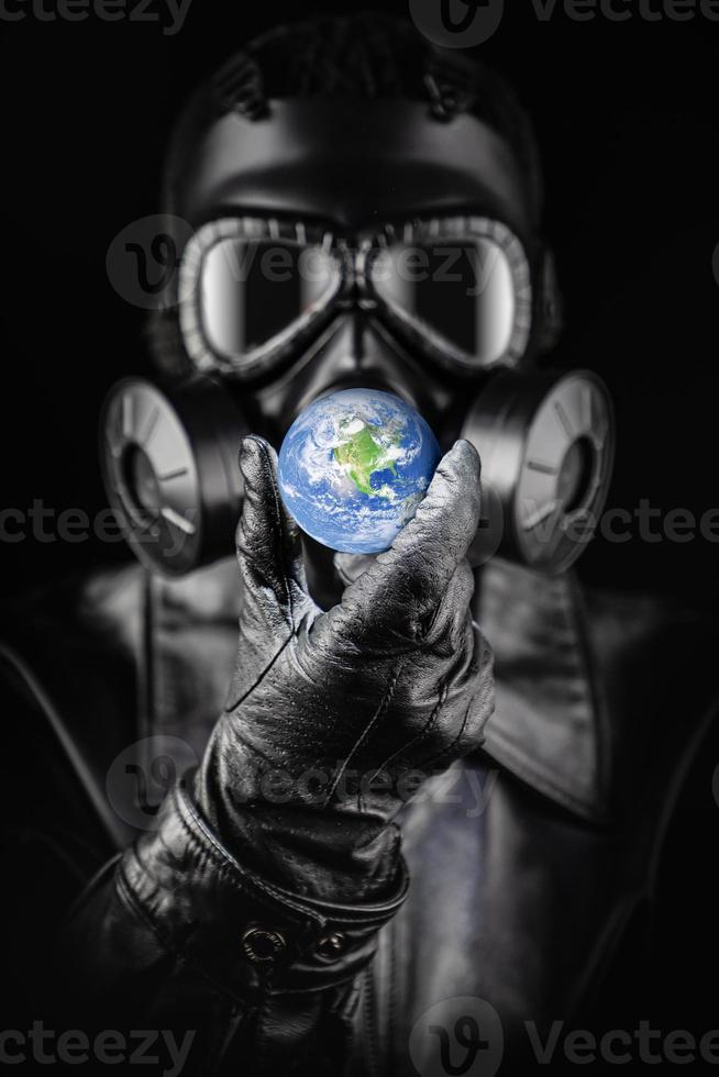 Menacing Entity Wearing Fallout Gas Mask Threatening Planet Earth With Gloved Hand photo