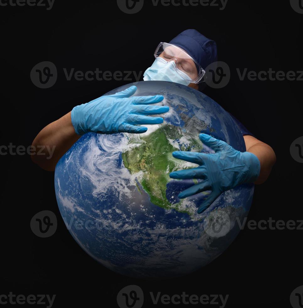 enfermera o médico con mascarilla y guantes quirúrgicos abrazando el planeta tierra foto