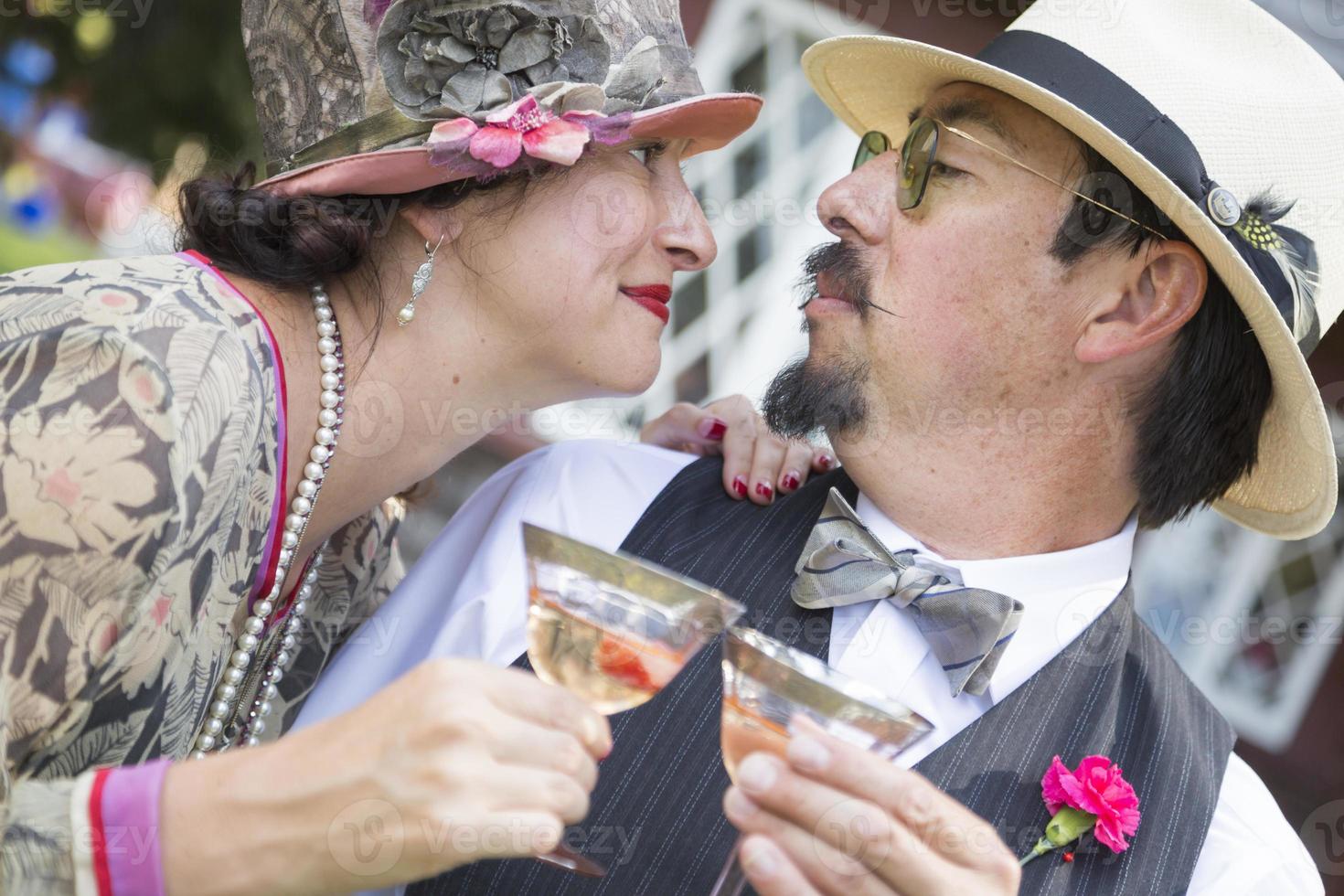 pareja de raza mixta vestida a la moda de la década de 1920 bebiendo champán foto