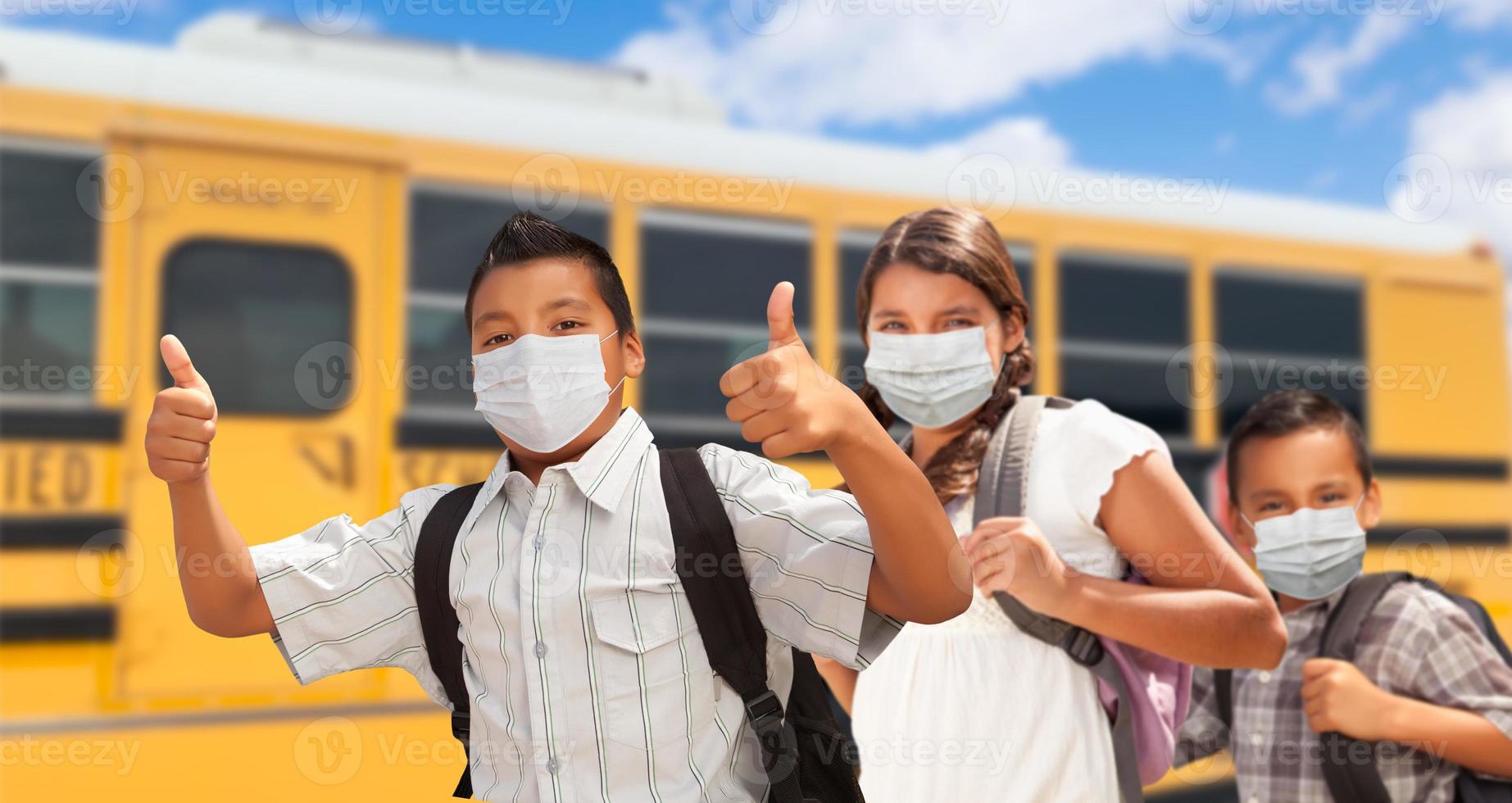 Hispanic Students Near School Bus Wearing Face Masks photo