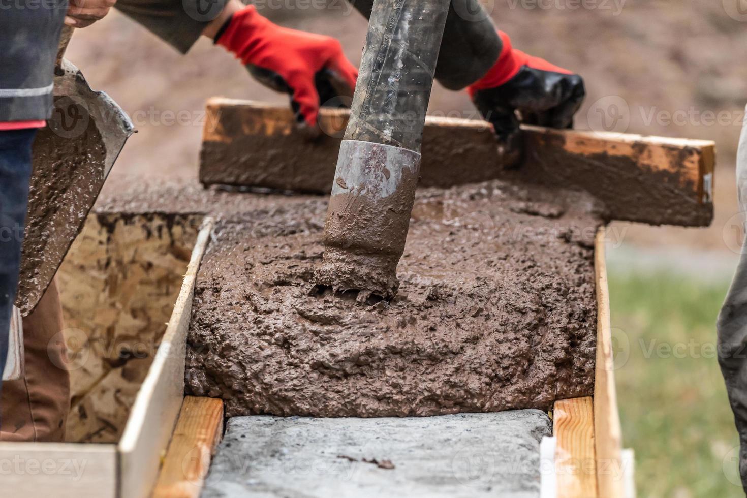 Construction Worker Leveling Wet Cement Into Wood Framing photo