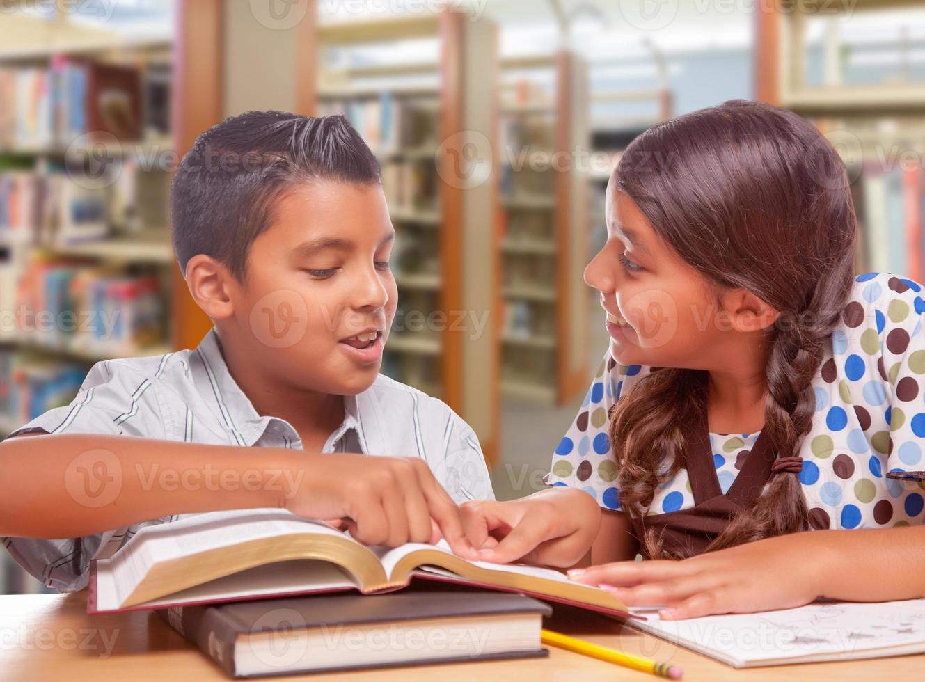 chico y chica hispanos divirtiéndose estudiando juntos en la biblioteca foto