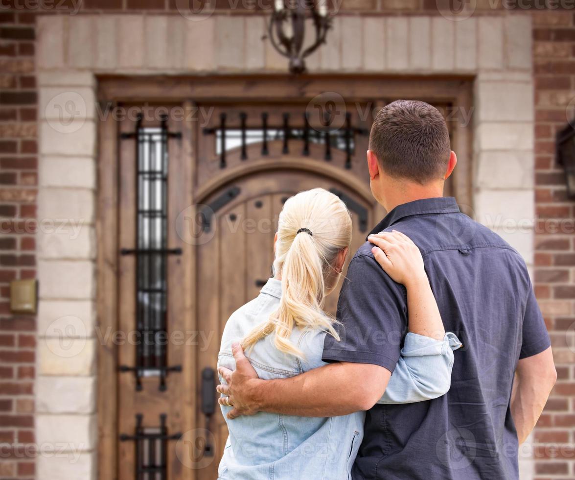 Happy Young Couple Facing Front Door of New House photo