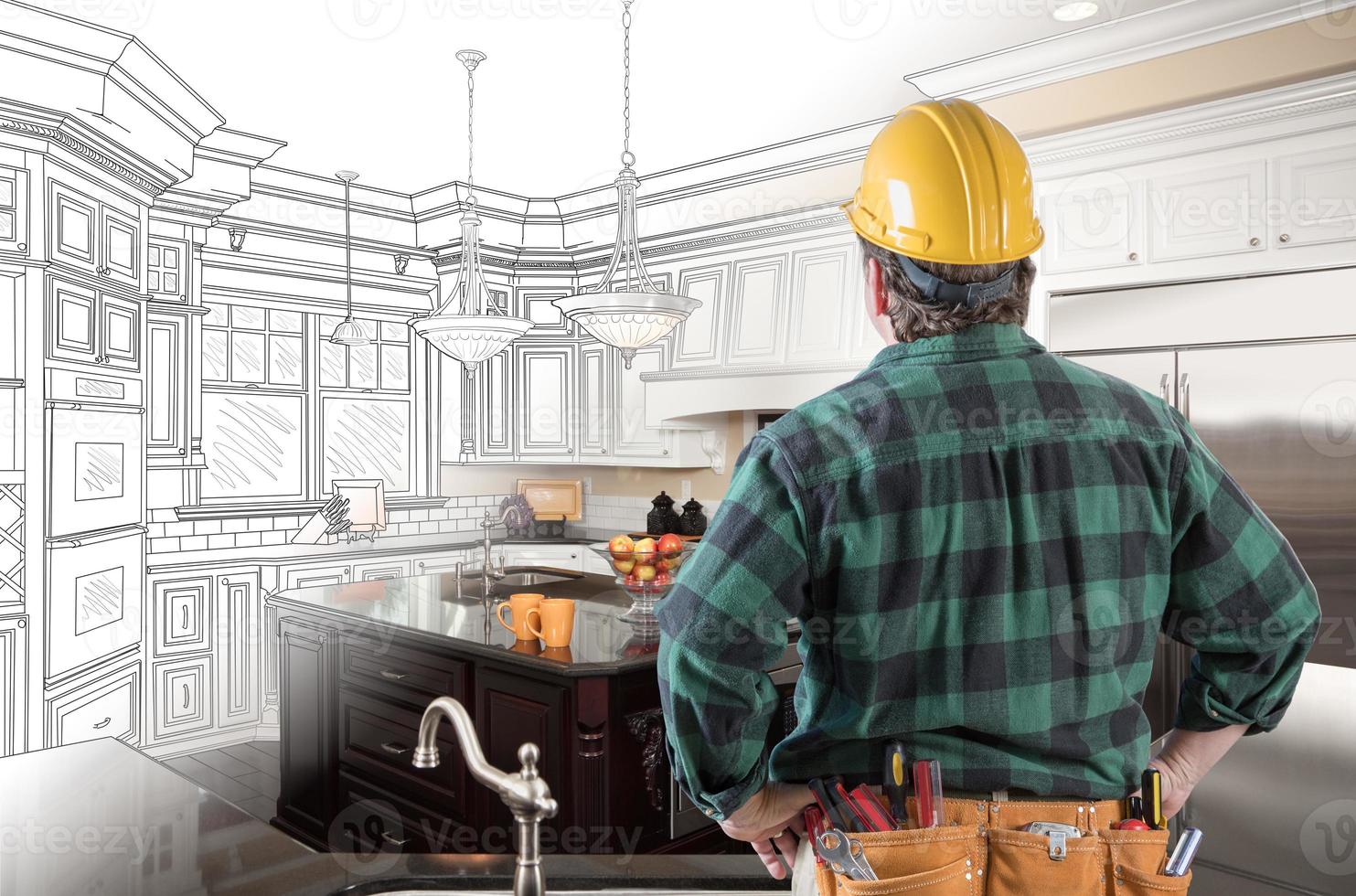 Male Contractor with Hard Hat and Tool Belt Looking At Custom Kitchen Drawing Photo Combination On White.