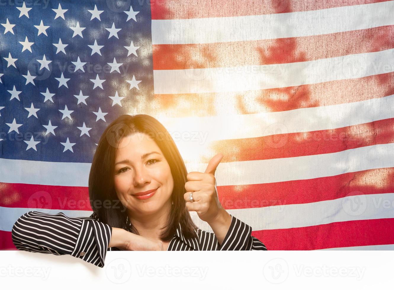 mujer hispana con los pulgares hacia arriba frente a la bandera americana foto